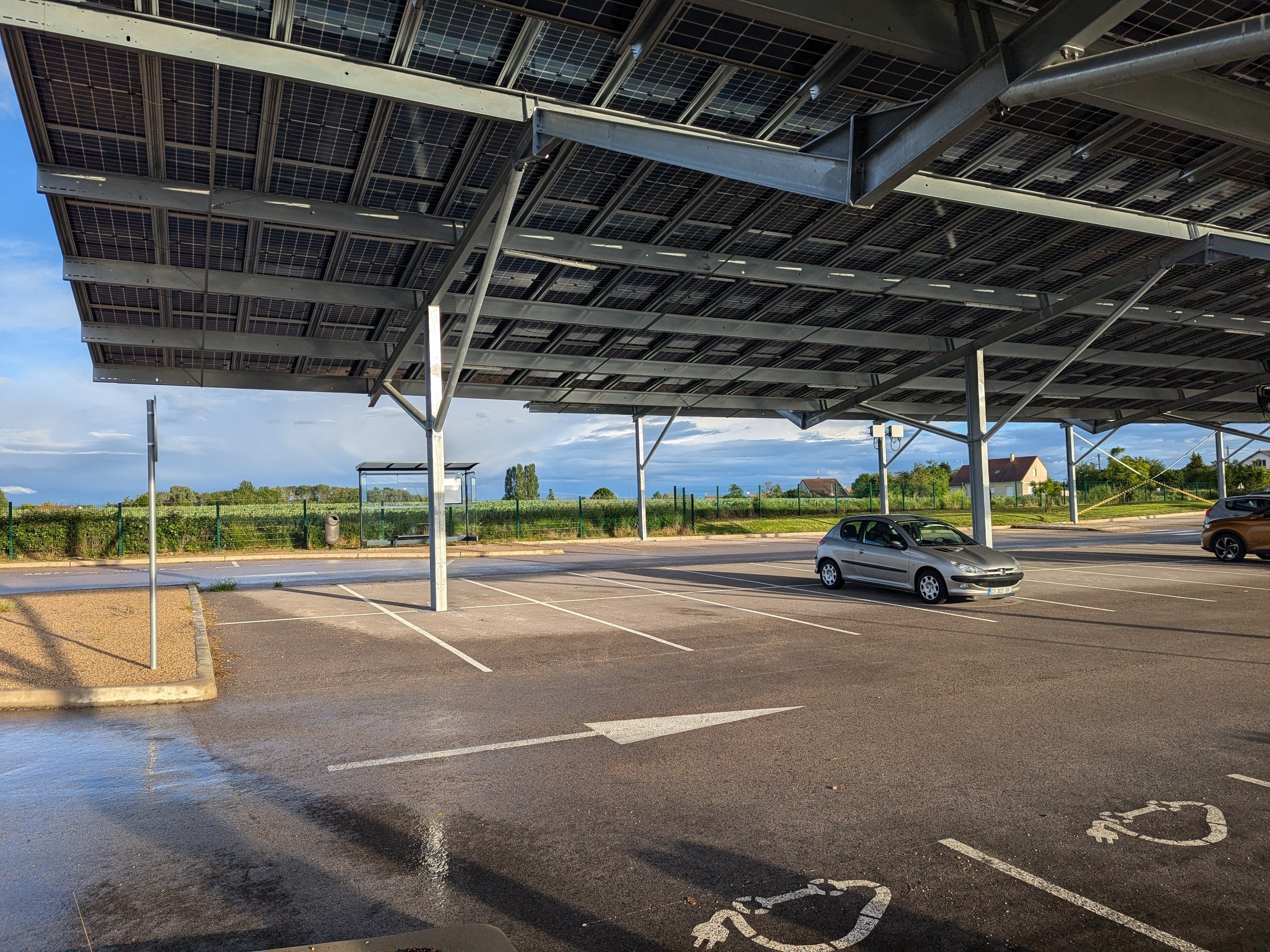Parking de covoiturage équipé d'ombrières solaires à proximité d’un axe routier.